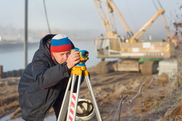 Mühendis inşaat sahasında ölçümleri leveli ile yapar — Stok fotoğraf