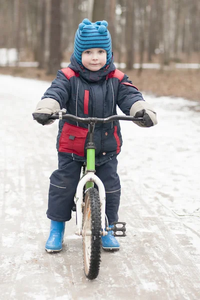 Little boy riding a bicycle in a park in winter — Stock Photo, Image