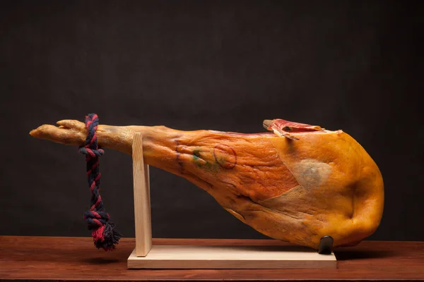 Hamon - leg of dried pork meat - on a wooden stand. — Stock Photo, Image
