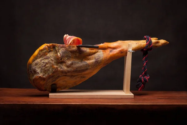 Hamon - leg of dried pork meat - on a wooden stand. — Stock Photo, Image