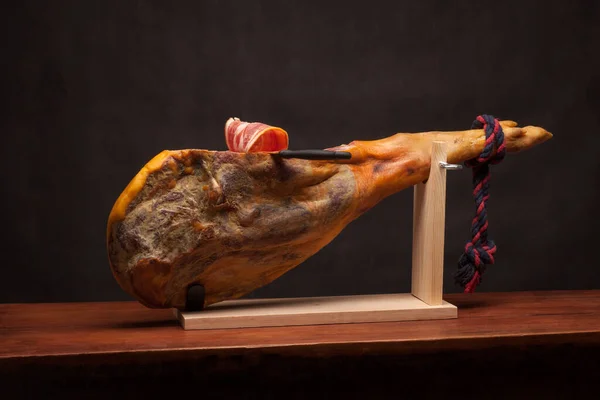 Hamon - leg of dried pork meat - on a wooden stand. — Stock Photo, Image