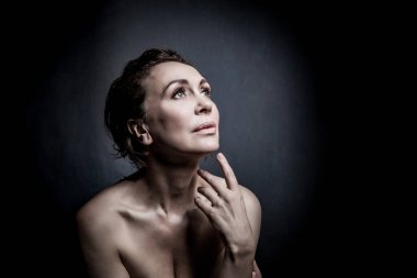 Gri stüdyo arka planında 50 yaşında şehvetli bir kadının portresi.