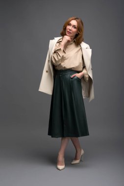 Gri arka planda soyutlanmış, modaya uygun yaşlı bir kadının tam boy portresi.