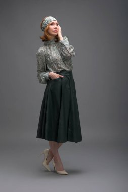 Gri arka planda soyutlanmış, modaya uygun yaşlı bir kadının tam boy portresi.