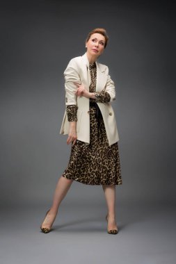 Gri arka planda soyutlanmış, modaya uygun yaşlı bir kadının tam boy portresi.