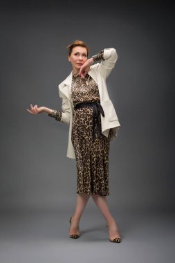 Gri arka planda soyutlanmış, modaya uygun yaşlı bir kadının tam boy portresi.