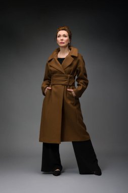 Gri arka planda soyutlanmış, modaya uygun yaşlı bir kadının tam boy portresi.