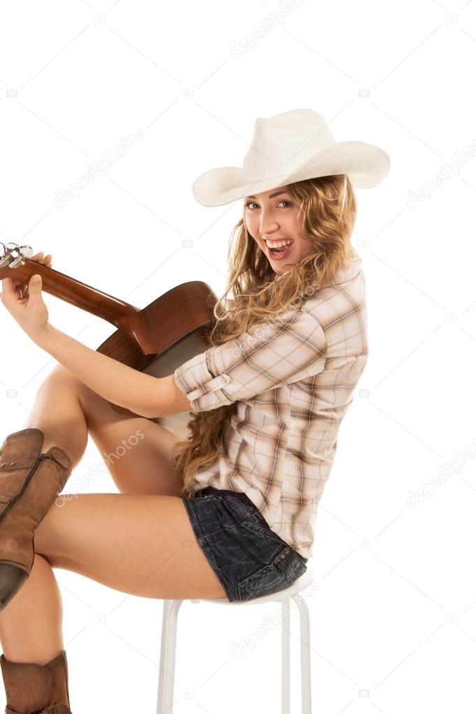 Sesy cowgirl in cowboy hat with acoustic guitar