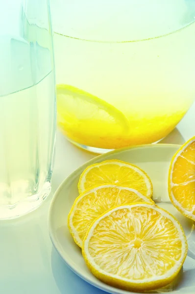 Lemon drink in a jug and glass, lies next to a lemon — Stock Photo, Image