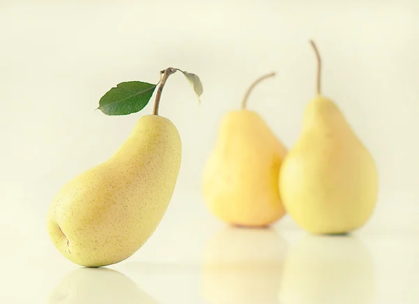 Reife Birne mit grünem Blatt auf Birnenhintergrund — Stockfoto