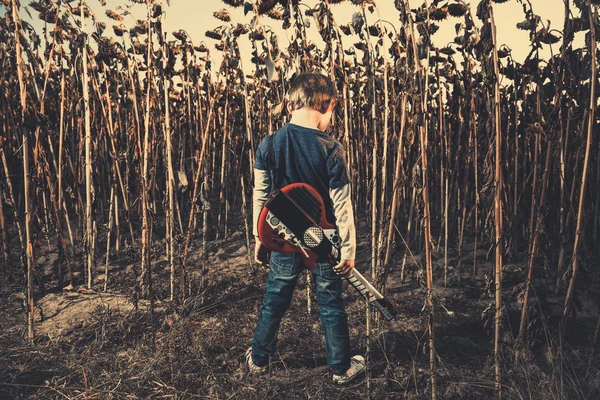 Little guitarist at dry sunflowers — Stock Photo, Image