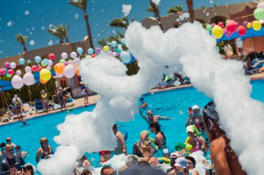 Mısır, Sharm el-Sheikh - 15.06.2021 Dansçı köpüklü otel partisi ve yüzme havuzunda eğlenen insanlar