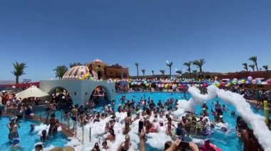 Mısır, Sharm el-Sheikh - 15.06.2021 yazlık otel tatil köyü dansçıları köpüklü parti ve yüzme havuzunda eğlenen insanlar