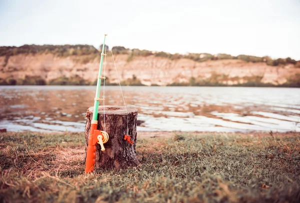 Toy rod at river bank — Stock Photo, Image