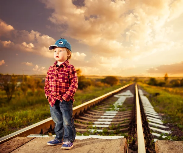 Jongen in hoed bij spoorweg zonsondergang — Stockfoto