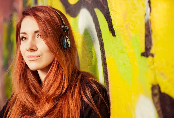 Redhead woman with earphones at graffiti — Stock Photo, Image