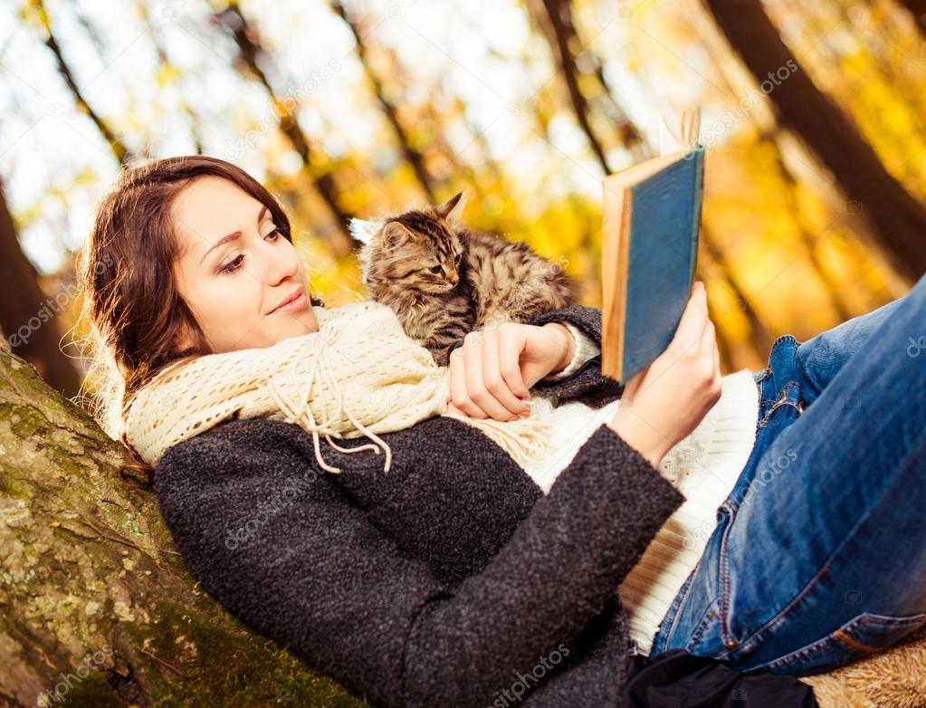 Brunet with cat reading book outside