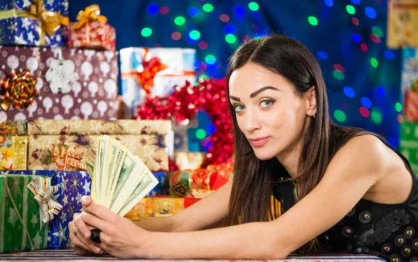 Женщина с деньгами на фоне рождественских подарков — стоковое фото