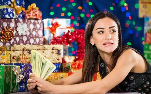 Woman with money at Christmas gifts background — Stock Photo, Image