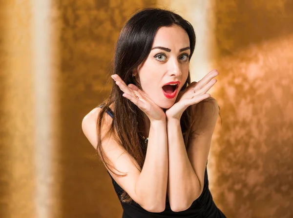 Surprised woman portrait at golden background — Stock Photo, Image