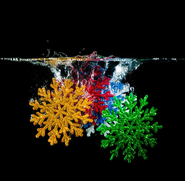 Copos de nieve de colores en el agua —  Fotos de Stock