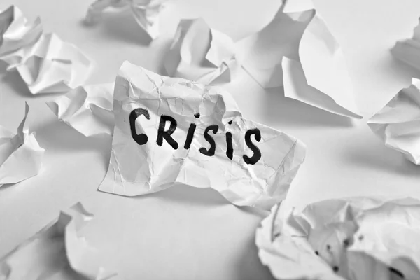 Verfrommeld vellen papier met het geschreven woord voor "crisis" — Stockfoto