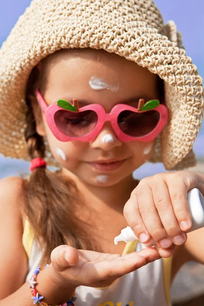 Fille dans des lunettes dégoulinant sur la crème solaire de la paume — Photo