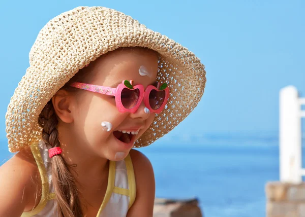 Niño feliz con gafas y protector solar en la cara contra el mar —  Fotos de Stock