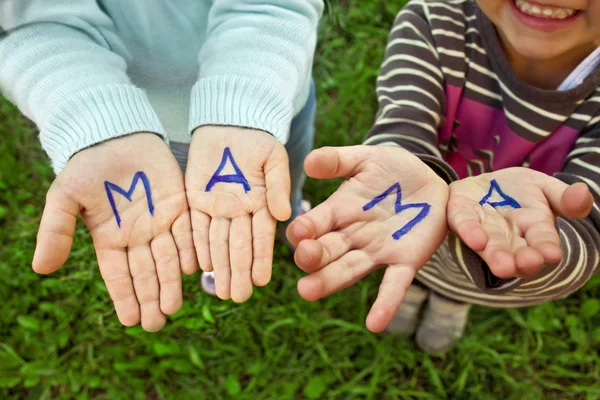 La palabra madre escrita en las manos de los niños — Foto de Stock