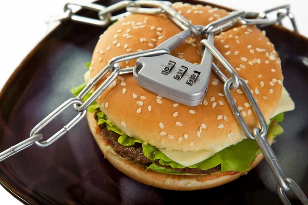 Burger, chained to the plate. Choosing a healthy diet. — Stock Photo, Image