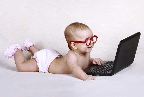 Gelukkig baby in glazen werkt op de computer — Stockfoto