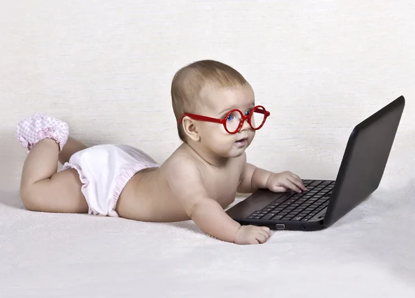 Funny kid with glasses with a computer Royalty Free Stock Photos