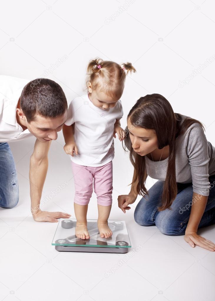 The little girl weighed on the scales next to their parents