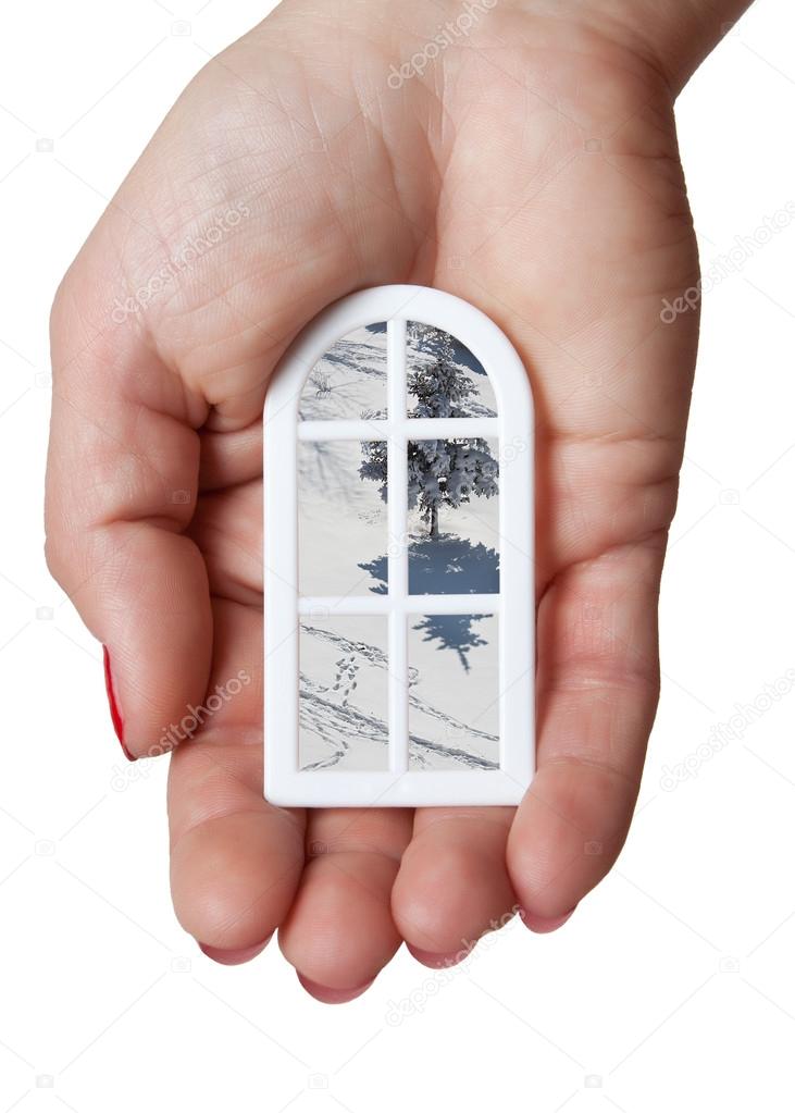 Model of a modern plastic window in hand with a view of the winter landscape