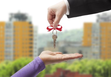 Handing the keys to the new owner on the background of the urban landscape clipart