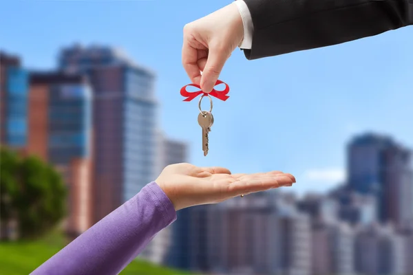 Handing the keys to the new owner on the background of the urban landscape — 图库照片