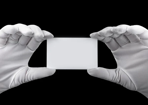 Hands in white gloves holding a white plastic card on black background — Stock Photo, Image