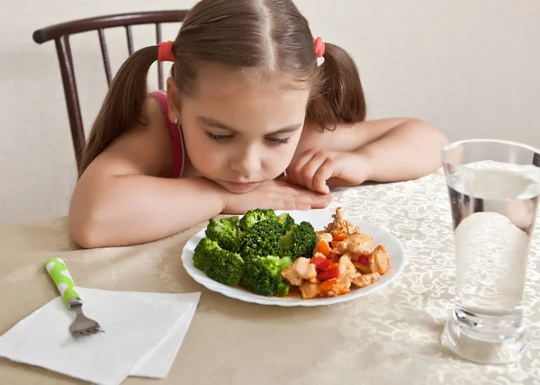 The girl looks indifferently at the dish with meat and broccoli — Stock Photo, Image