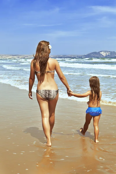 A woman with a child by the hand along the sea shore — Stock Photo, Image