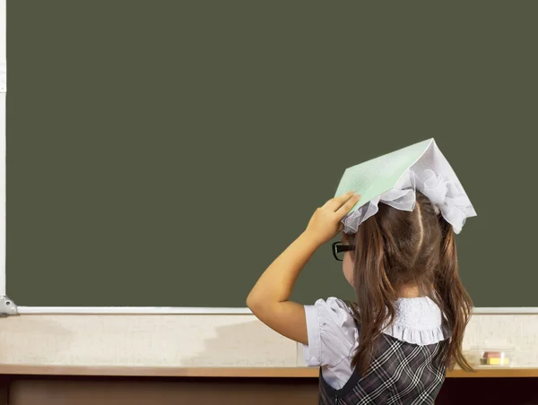 Schoolmeisje op het bord met een laptop op zijn hoofd — Stockfoto