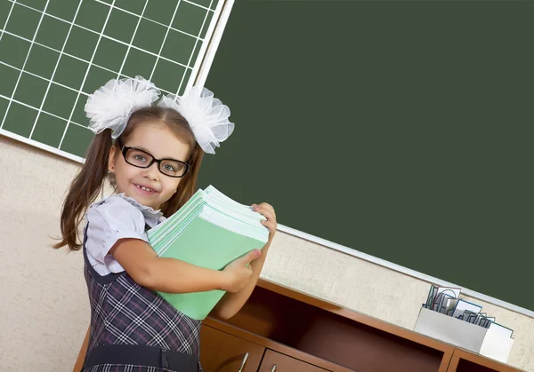 Plicht gelukkig schoolmeisje met stapel boeken op het bord — Stockfoto