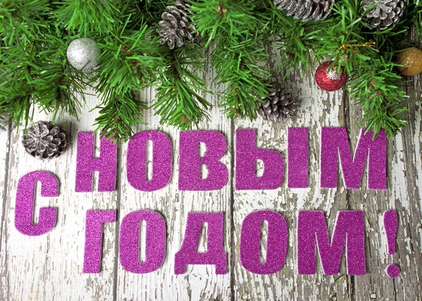 Napis w języku rosyjskim "Szczęśliwego nowego roku" z gałęzie jodły na białe ściany drewniane — Zdjęcie stockowe