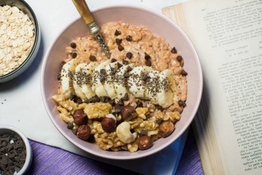 Bir kase yulaf lapası, muz ve fındıklı. Üst Manzara. Sağlıklı vejetaryen kahvaltısı