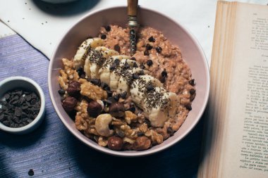 Bir kase yulaf lapası, muz ve fındıklı. Üst Manzara. Sağlıklı vejetaryen kahvaltısı