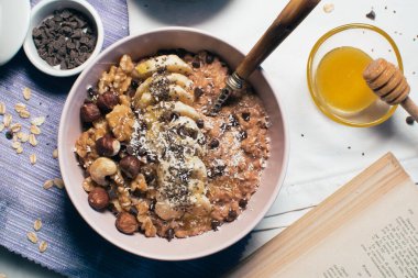 Bir kase yulaf lapası, muz ve fındıklı. Üst Manzara. Sağlıklı vejetaryen kahvaltısı