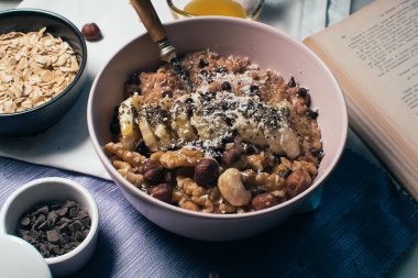 Bir kase yulaf lapası, muz ve fındıklı. Üst Manzara. Sağlıklı vejetaryen kahvaltısı