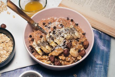 Bir kase yulaf lapası, muz ve fındıklı. Üst Manzara. Sağlıklı vejetaryen kahvaltısı