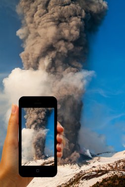 Tourist photographing the volcano eruption on smartphones clipart