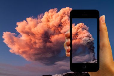 Tourist photographing the volcano eruption on smartphones