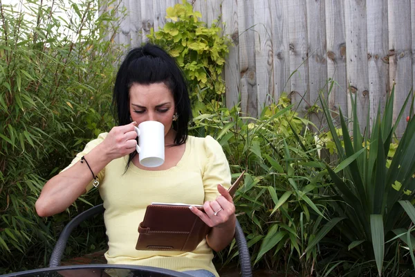 Женщина в саду читает — стоковое фото
